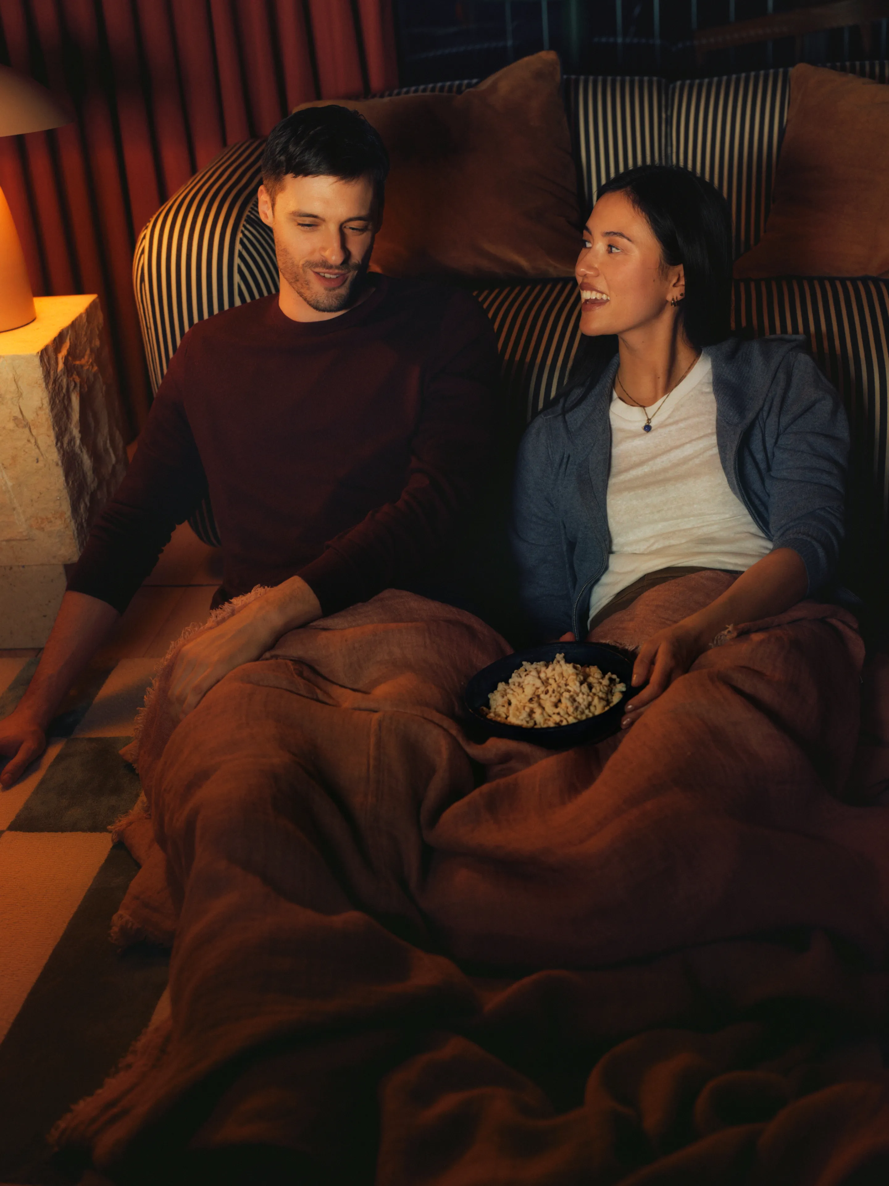 Couple watching a film under a blanket with popcorn